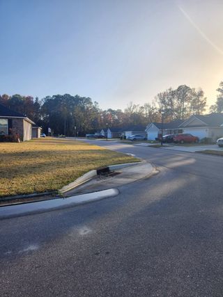 A view down the street in the Summerglen neighborhood by Adams Homes (Jacksonville, FL), showing neatly aligned homes along the street, with trees and clear skies.