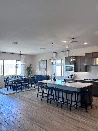Model Home A modern kitchen with a large island, sleek dark cabinets, and a dining area with elegant pendant lighting.