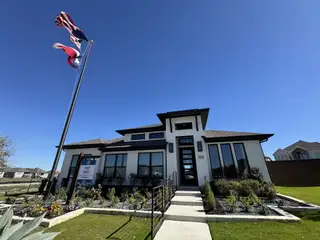 A modern white brick home with sleek windows and landscaped yard in Homestead 55' by Perry Homes (Schertz, TX).