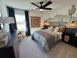 Model Home A cozy bedroom featuring desert-themed wall art, elegant lighting, and a stylish black ceiling fan.
