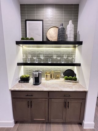 A chic coffee nook with marble countertop, black shelves, stylish decor, and modern cabinetry.