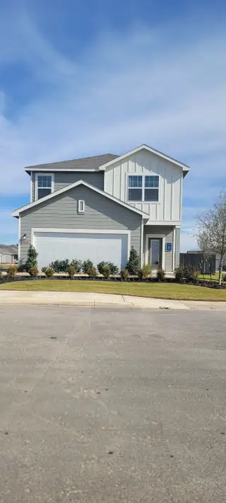 Street view A modern gray two-story home with a landscaped yard in Sutton Farms by Starlight Homes (San Antonio, TX).