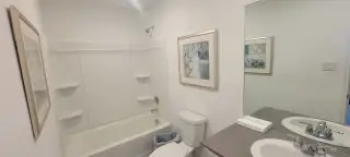 A sleek bathroom with a tub-shower combo, modern vanity, and stylish wall art.