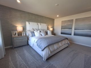 A cozy bedroom featuring a soft gray palette, elegant bedding, and stylish abstract art on the wall.