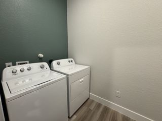 A sleek laundry room featuring modern washer and dryer against a textured green accent wall.