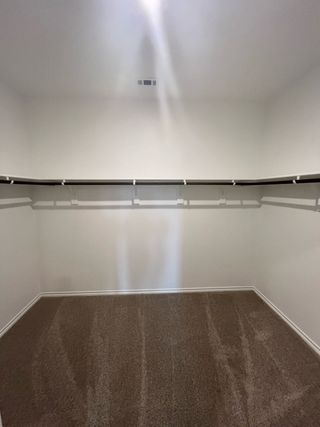 A spacious walk-in closet with plush carpet and dual hanging rods, ideal for organized storage and convenience.