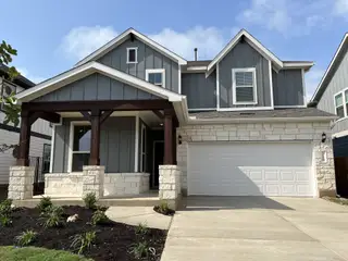 A charming gray and white home with a stone facade in Santa Rita Ranch by Pulte Homes (Liberty Hill, TX).