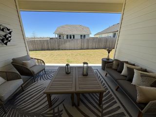 Street view A cozy patio with stylish seating, decorative pillows, and outdoor decor overlooking a fenced backyard.