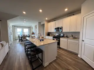 Modern kitchen with sleek white cabinets, granite island, and cozy dining area by the window.