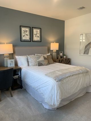A cozy bedroom featuring a gray accent wall, elegant decor, and a plush bed with warm lighting for a relaxing ambiance.