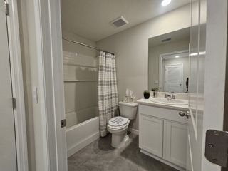 A cozy bathroom featuring a tub-shower combo, sleek vanity, and modern fixtures, enhanced by soft lighting and neutral tones.