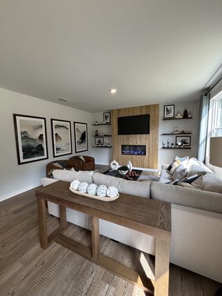 A cozy living room featuring a sectional sofa, textured wall with a TV, and elegant decor accents.