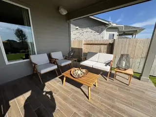 Model Home A cozy patio featuring wooden furniture, comfortable seating, and stylish decor, perfect for outdoor relaxation.