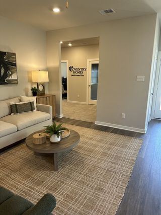 Model Home A cozy living room featuring a beige sofa, stylish round table, and textured rug, offering a warm and inviting atmosphere.