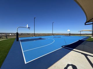 A vibrant blue basketball court under clear skies in Rancho Del Cielo by Lennar (Jarrell, TX).