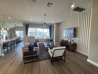 A spacious living area with a cozy sectional, sleek TV console, and open dining area with modern lighting.