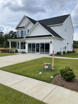 A charming white home with a black roof and manicured lawn in Parker's Preserve by Eastwood Homes (Ridgeville, SC).