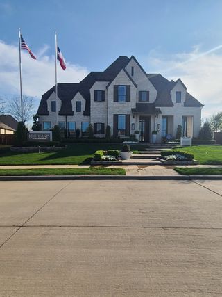 Street view A stunning white brick home with lush landscaping in Star Trail: 86ft. lots by Highland Homes (Prosper, TX).