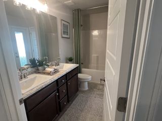 A modern bathroom featuring dual sinks, a stylish vanity, and a classic tub.
