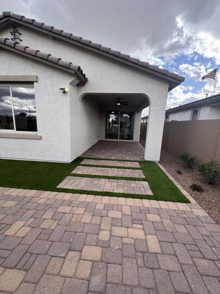 Street view A modern home with arched entry and paved walkway in Seasons at Trevino II by Richmond American Homes (Glendale, AZ).