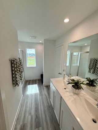 A bright bathroom featuring wood-style flooring, a sleek white vanity, and modern fixtures with abundant natural light.