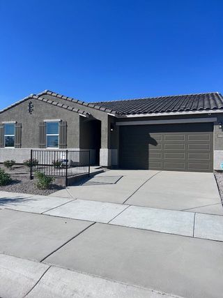 Model Home A modern stucco home with a tiled roof and manicured yard in Silva Farms by Meritage Homes (Goodyear, AZ).