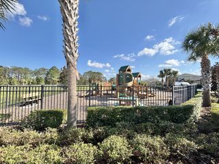 A lovely playground surrounded by lush greenery and palm trees in Harmony West by D.R. Horton (St. Cloud, FL).