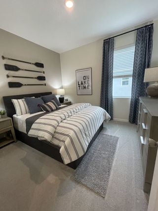 A cozy bedroom with nautical decor, featuring striped bedding and sleek furniture, complemented by soft lighting and carpets.