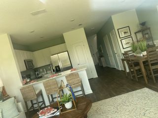 A cozy open-plan kitchen and dining area featuring wooden floors, modern appliances, and chic decor with green accents.