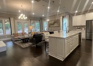 Model Home An elegant open-concept living area with hardwood floors, modern lighting, and a spacious kitchen island.