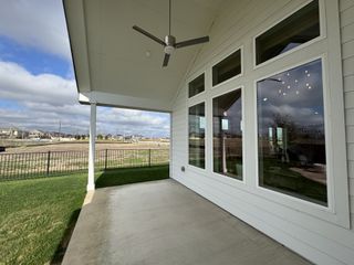 Model Home A covered patio with large windows and scenic views in August Fields by Chesmar Homes (New Braunfels, TX).