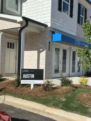 Street view A chic brick-front home with elegant shutters and a manicured garden in Diamante by DRB Homes (Stockbridge, GA).