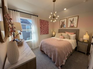 A whimsical bedroom decorated with soft pinks, pom-pom bedding, and bunny artwork.