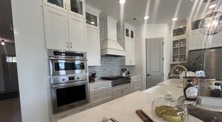 Model Home A sleek kitchen with white cabinetry, stainless appliances, and a chic backsplash design.