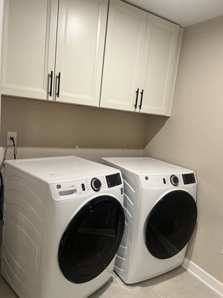 A functional laundry room with sleek white cabinets, modern washer, and dryer.