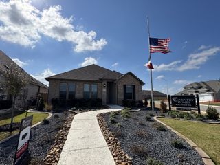 Street view A charming brick home with a manicured yard in Sunflower Ridge by Coventry Homes, New Braunfels, TX.