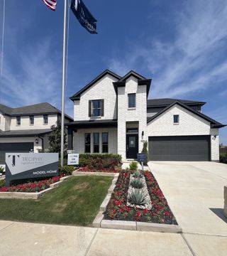 Street view A beautiful white brick home with elegant landscaping in Tesoro at Chisholm Trail Ranch by Trophy Signature Homes (Fort Worth, TX).