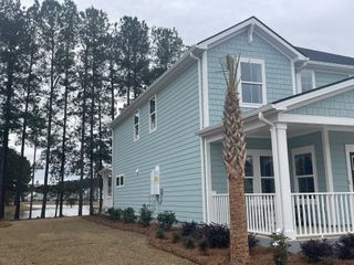 A charming blue home with a wrap-around porch in The Coves at Lakes of Cane Bay by Meritage Homes (Summerville, SC).