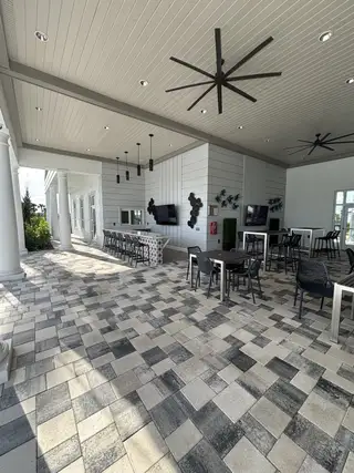 A sleek tiled outdoor space with modern ceiling fans, bar seating, and decorative elements.
