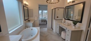 Model Home A luxurious bathroom with a freestanding tub, dual vanities, a makeup vanity, and a glass-enclosed shower, in a Stillwater Ranch home by Coventry Homes (San Antonio, TX).