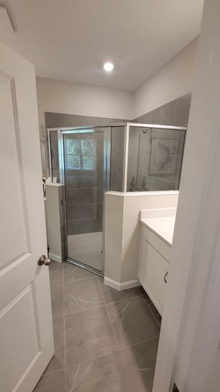 Model Home A sleek bathroom with a glass-enclosed shower, elegant gray tiles, and a bright, modern vanity.