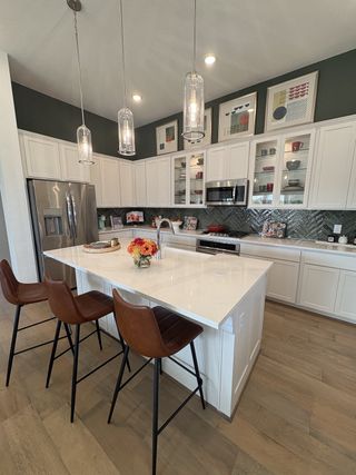 Model Home A modern kitchen with sleek cabinetry, quartz island, pendant lighting, and stylish bar stools.