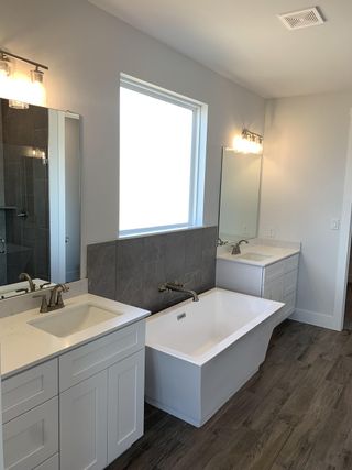 A sleek bathroom featuring dual vanities, a modern freestanding tub, and elegant lighting.