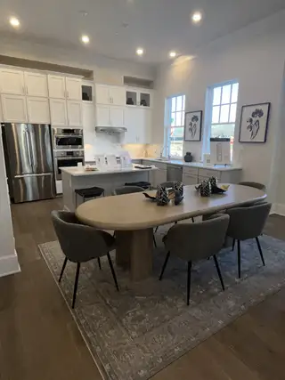 A modern kitchen with white cabinetry, a stainless steel fridge, and a sleek dining setup on a stylish rug.