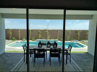 Chic outdoor space with a sleek table, modern chairs, and a refreshing pool view, perfect for entertaining and relaxation.