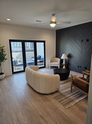 A sleek modern lounge with a bold black accent wall, plush seating, and glass doors opening to a private patio.