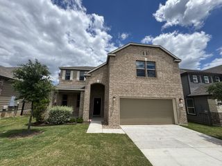 A beautiful brick home with a manicured lawn in McKinney Crossing by KB Home (Austin, TX).