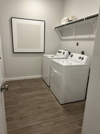 A functional laundry room with modern appliances, wood-style flooring, and minimalist artwork.