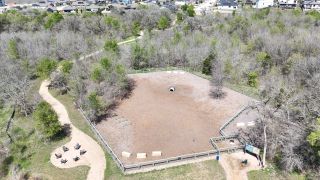 Aerial view of a fenced park with trails and seating in Whisper Valley by AHA Dream Homes, LLC (Manor, TX).
