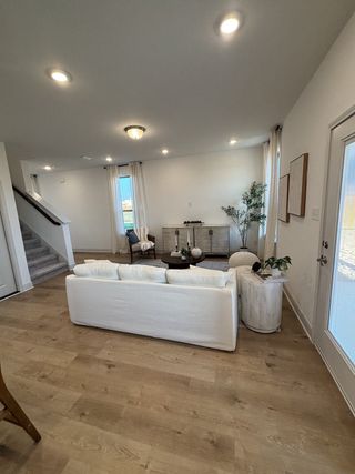A stylish living area with wood flooring, a cozy white sofa, and elegant décor in Blue Ridge Ranch by Rosehaven Homes (San Antonio, TX).